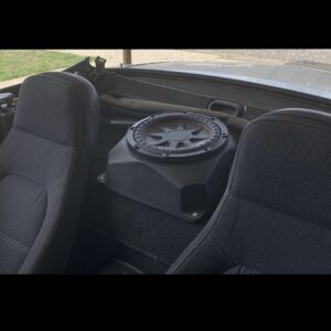 Car interior with two seats and subwoofer.